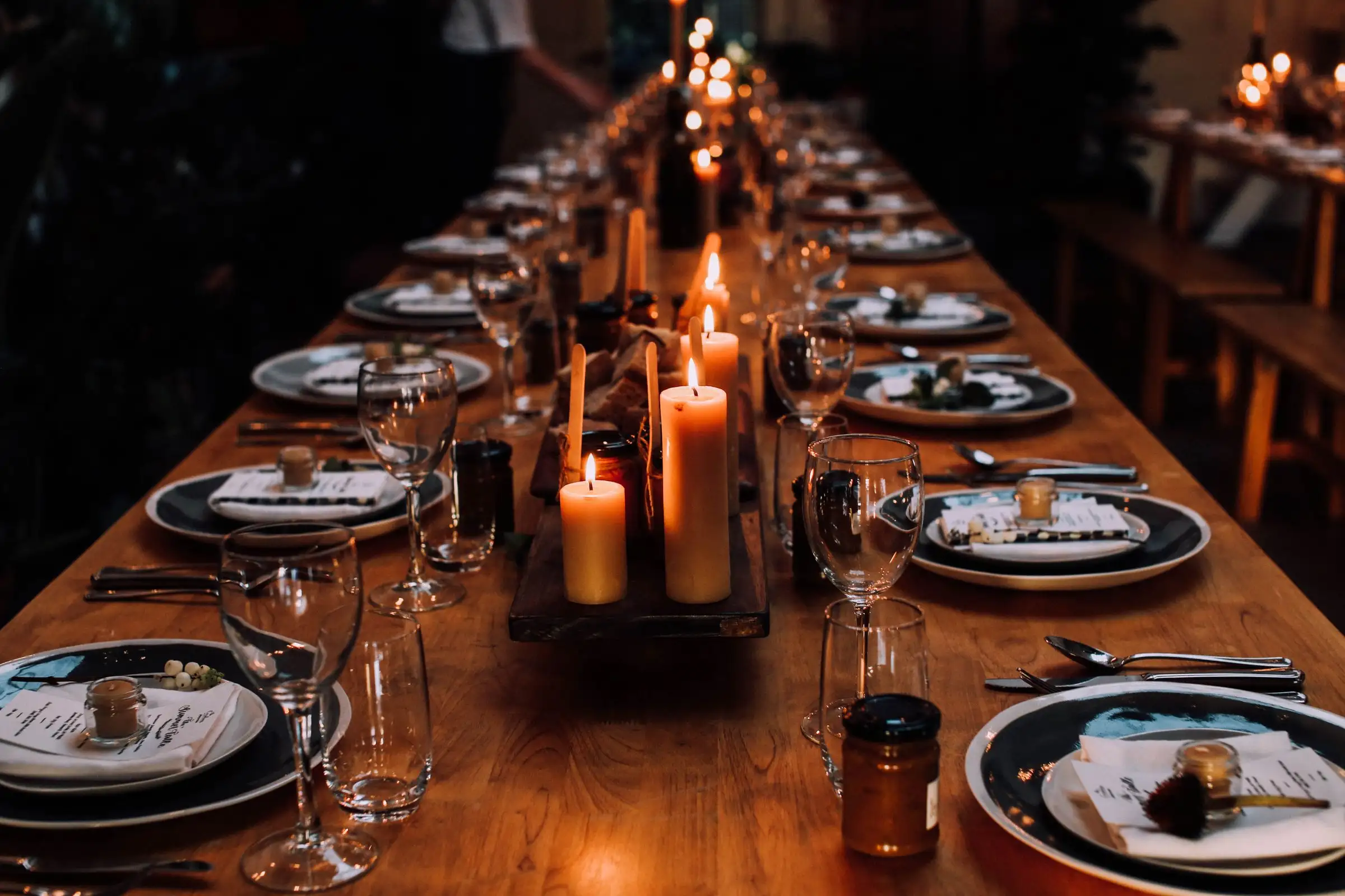 A long banquet table set with plates, glassware, and lit candles